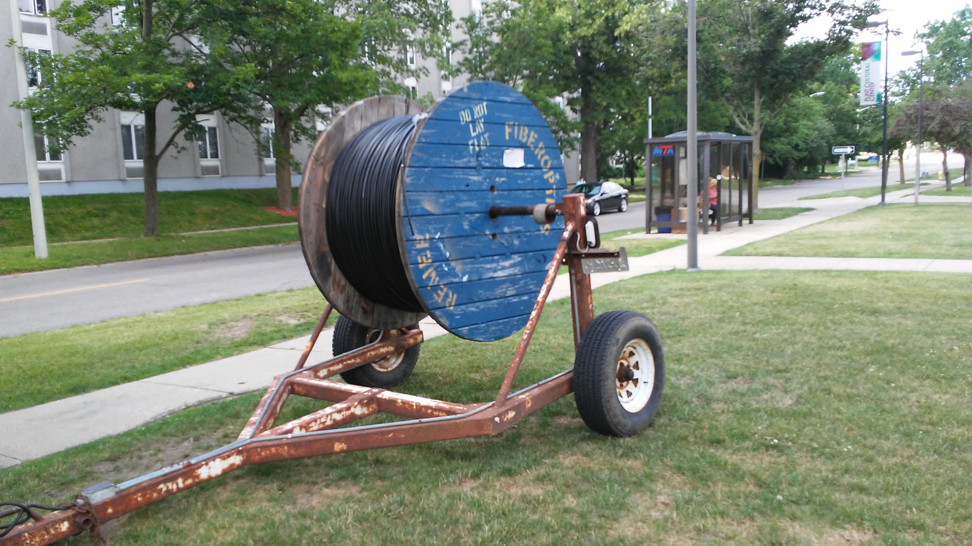 Large blue fiber spool on trailer used for laying fiber optic cable in Flint neighborhood.