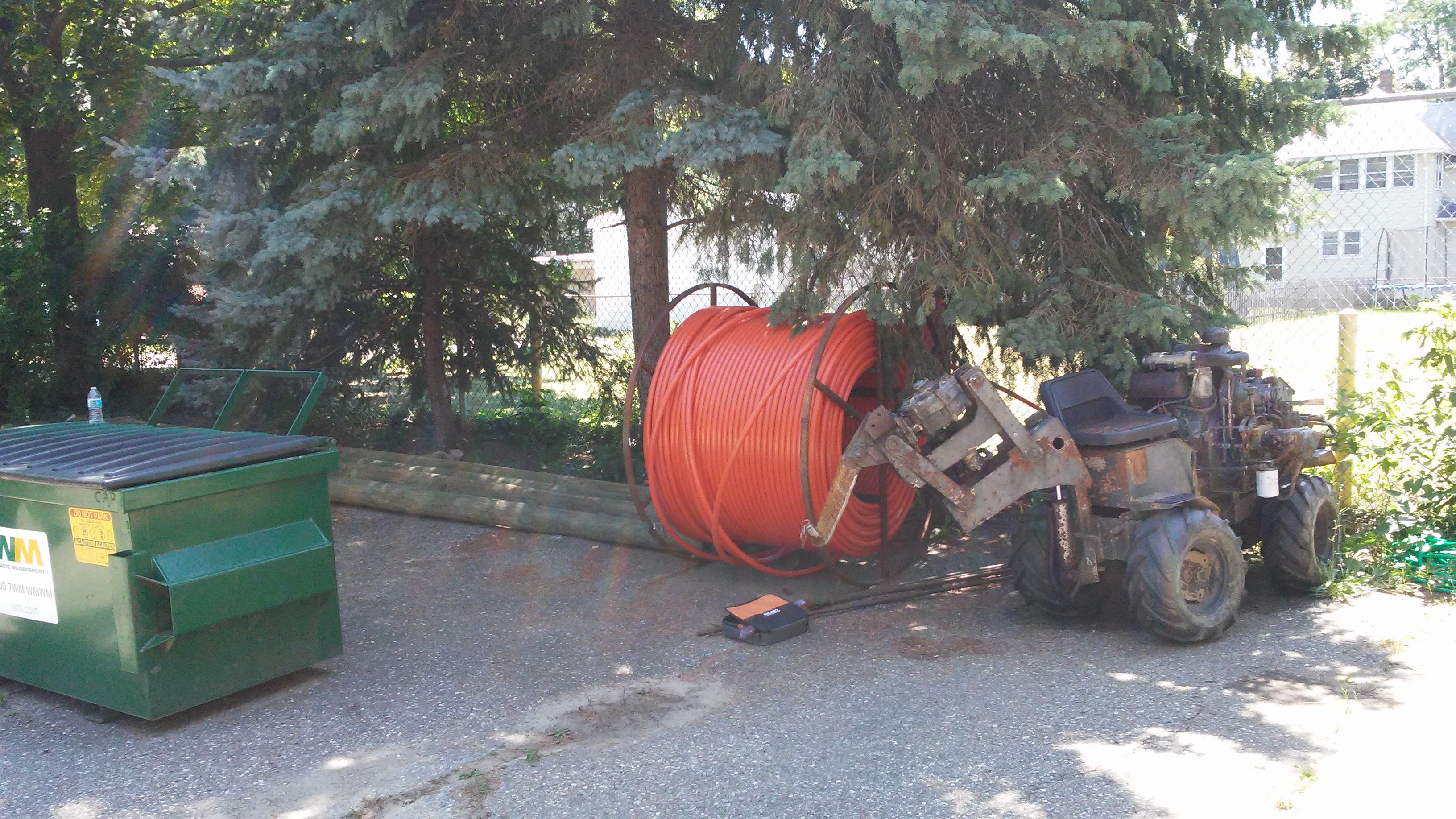 Orange fiber conduit and small trenching equipment staged for deployment.