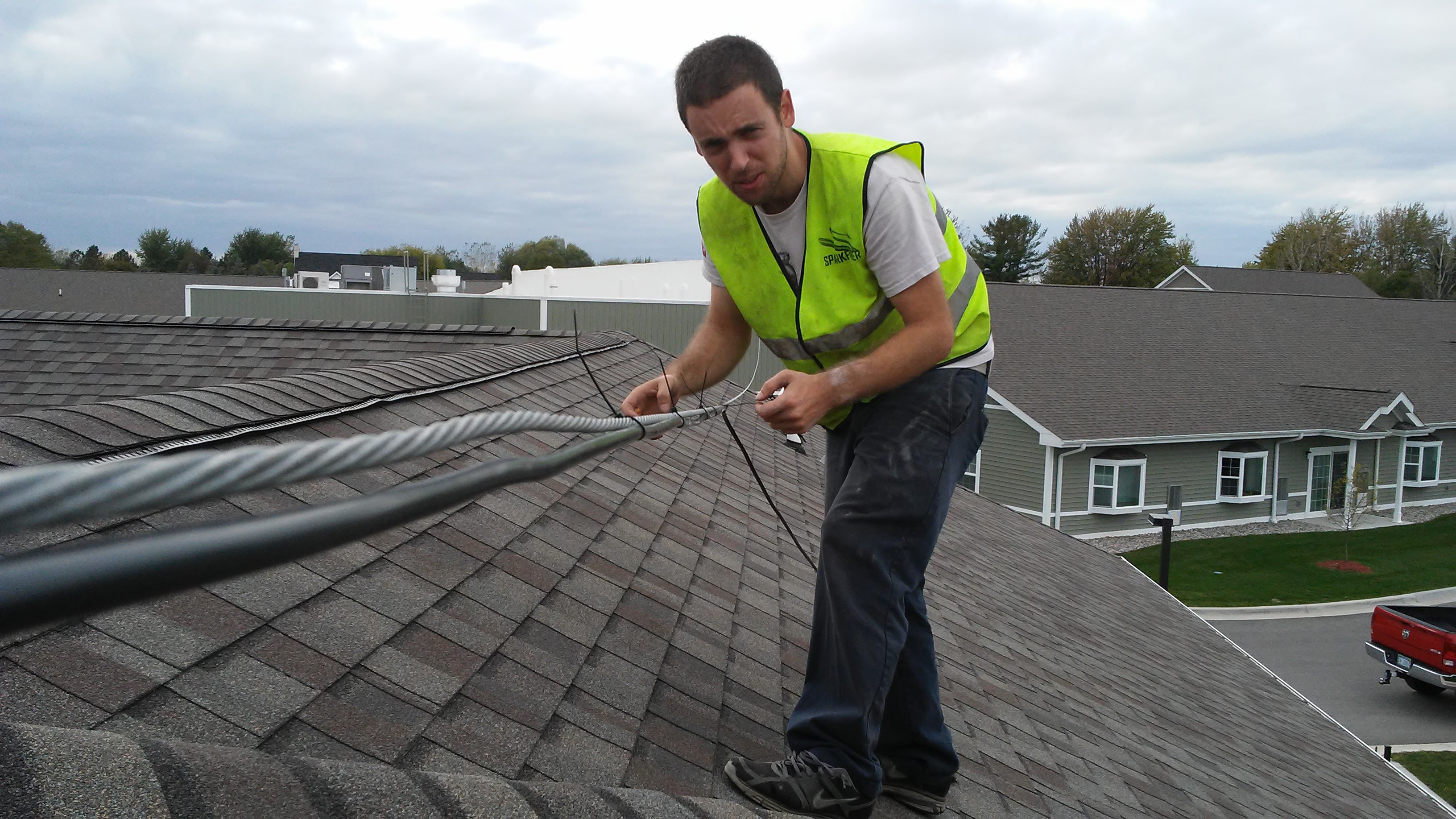 Team member on rooftop securing fiber cable for aerial installation.